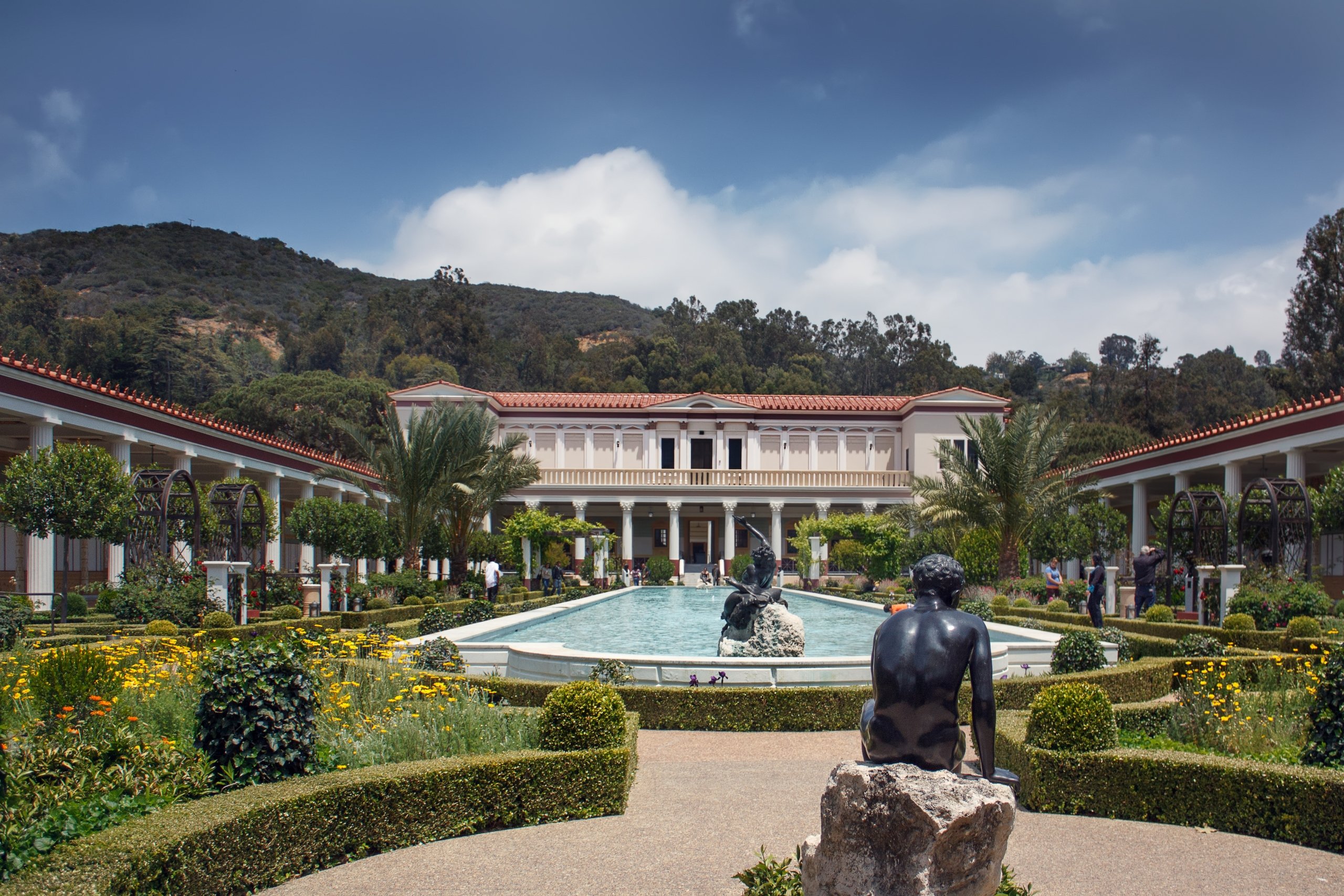 Getty Villa show casing a large outdoor pond and statues with large mountains in the background