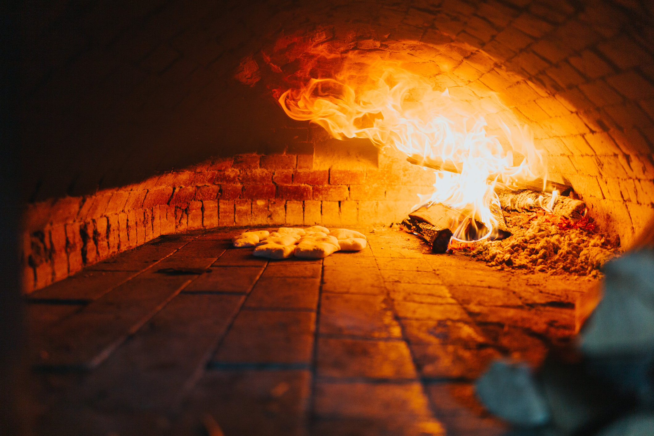 A closeup view of a wood fire oven baking some bread at Tar & Roses