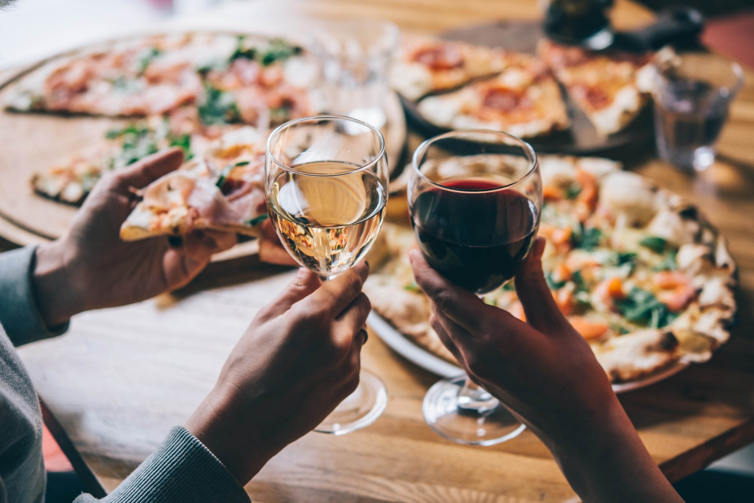 Two people enjoying some pizza and wine